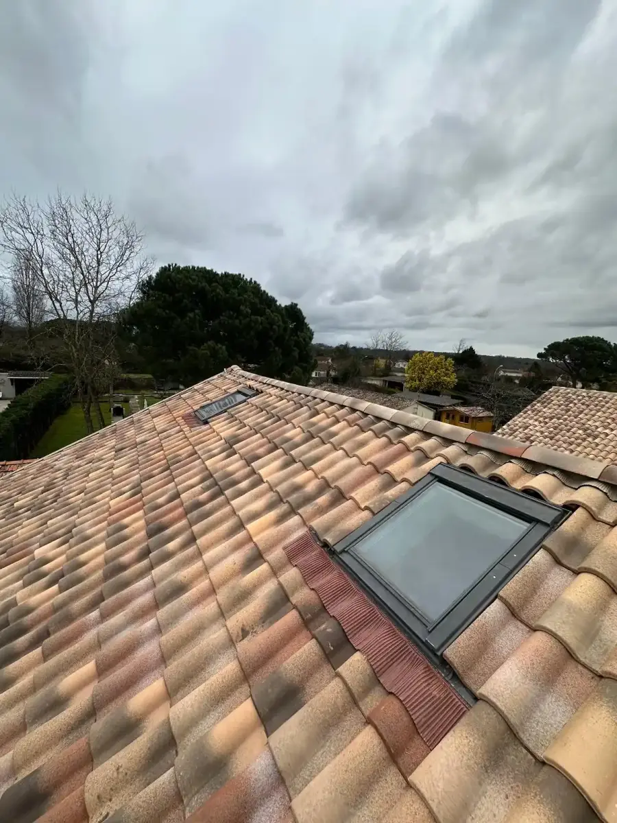 Toiture en tuiles rénovée, équipée d'une fenêtre de toit, sous un ciel couvert