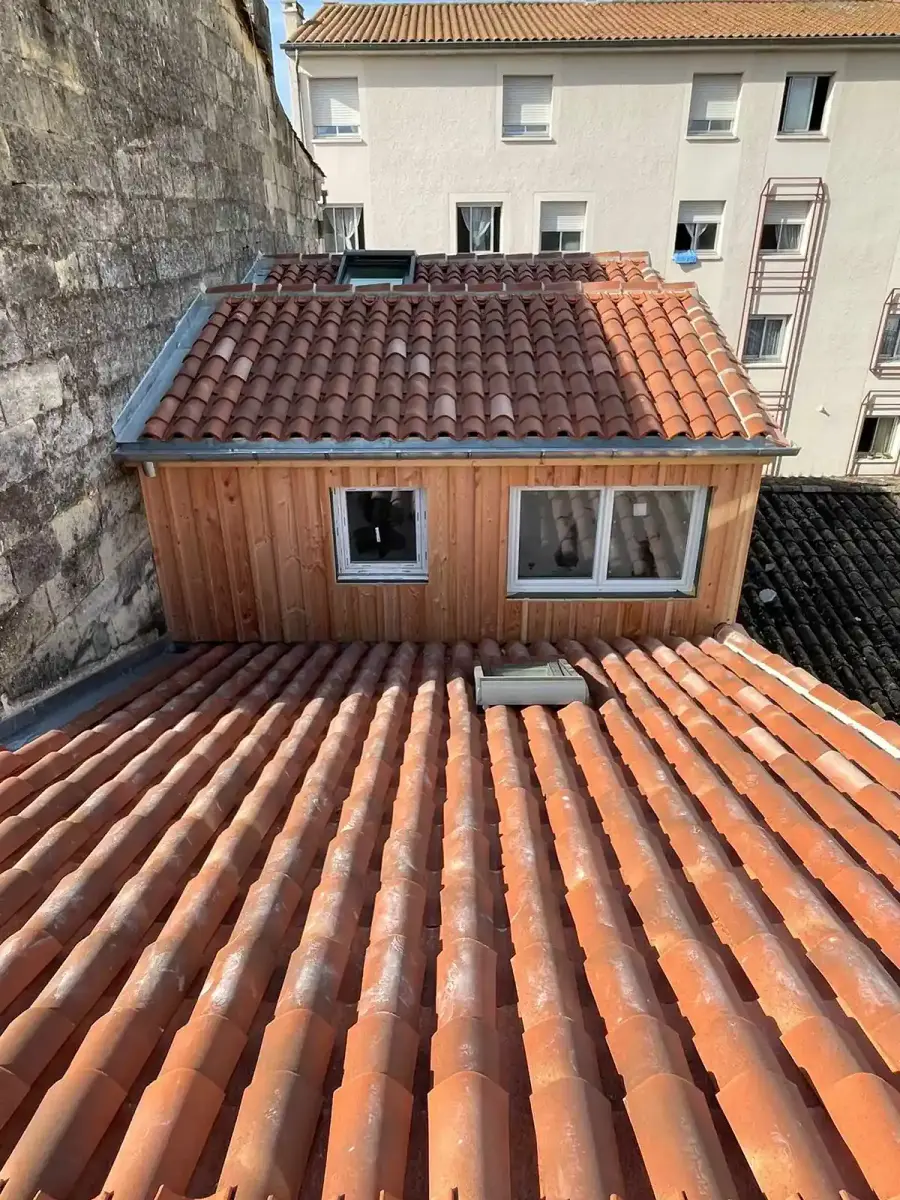 Lucarne habillée de bardage bois, posée sur une toiture ancienne en tuiles canal