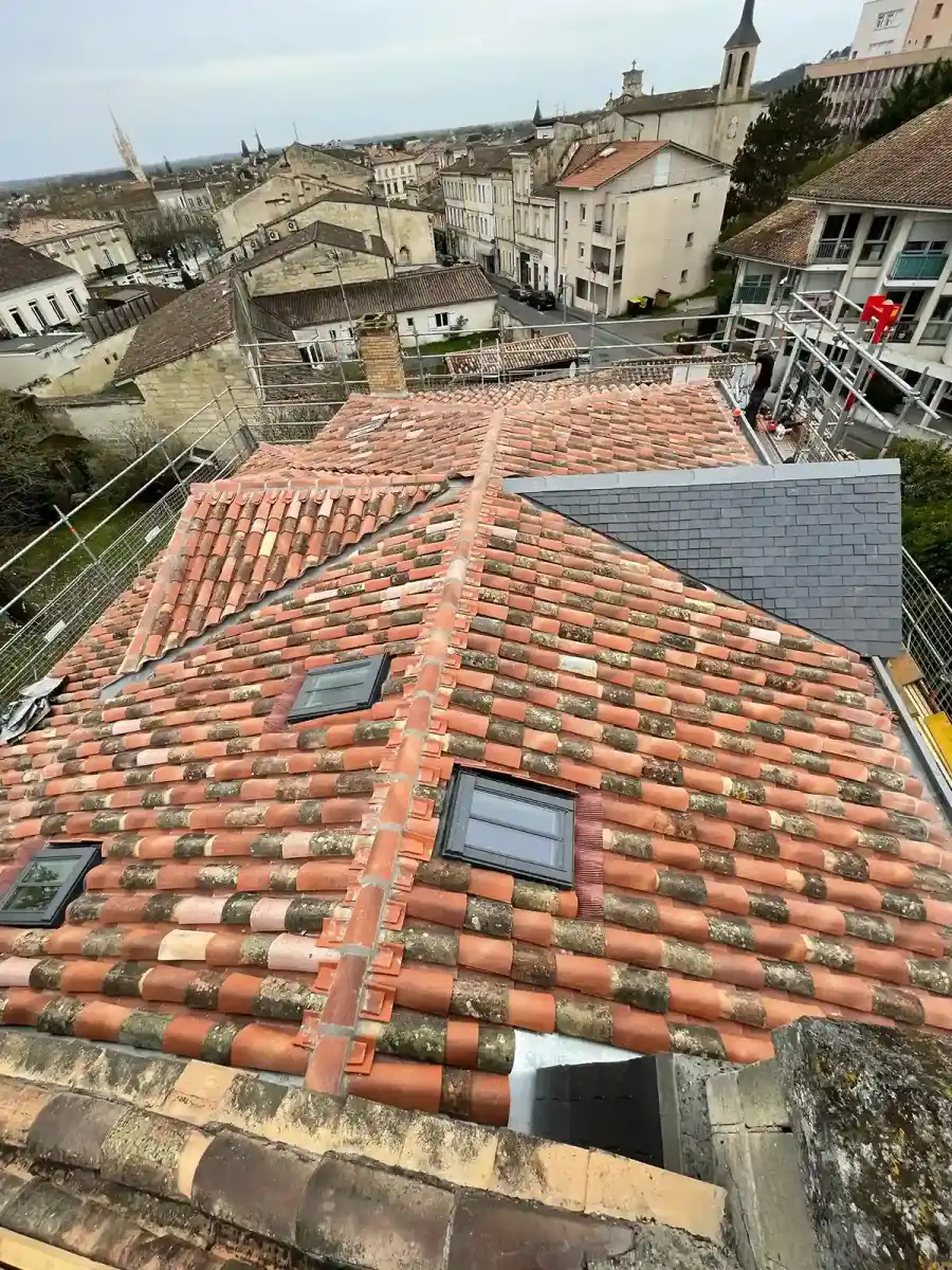 Toiture en tuiles restaurée et équipée de fenêtres de toit, dominant un village girondin